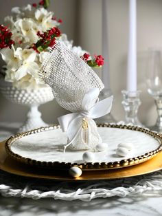 a white and gold plate topped with a bouquet of flowers next to a vase filled with red and white flowers