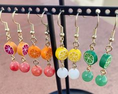 a bunch of fruit earrings hanging from hooks