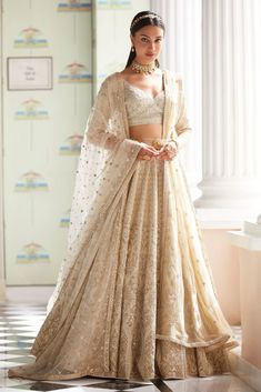 a woman in a white and gold lehenga