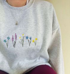 The Wildflowers Embroidered Sweatshirt 2D Crewneck Sweatshirt is the perfect blend of comfort, style, and elegance for both men and women. Crafted with meticulous attention to detail, this sweatshirt is designed to make a bold fashion statement while keeping you cozy and warm. Featuring an exquisite embroidered wildflowers design, this sweatshirt showcases the beauty of nature in a unique and artistic way. The vibrant colors and intricate stitching bring the wildflowers to life, adding a touch o Spring Long Sleeve Tops With Embroidered Logo, Long Sleeve Tops With Embroidered Logo For Spring, Cotton Sweater With Floral Embroidery, Spring Crew Top With Embroidered Logo, Spring Crew Neck Sweatshirt With Embroidered Logo, Spring Sweatshirt With Embroidered Logo And Crew Neck, Spring Crew Neck Sweater With Embroidered Logo, Spring Crew Sweatshirt With Embroidered Logo, Casual Cotton Sweatshirt With Floral Embroidery