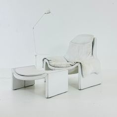 a white chair and footstool sitting next to each other on a white floor