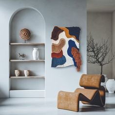 a living room with two chairs and a rug hanging on the wall next to shelves