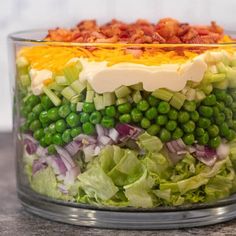 a salad with peas, lettuce and bacon in a glass bowl