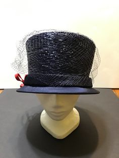 "This is a vintage 1960s Doris Designed navy blue straw hat with netting, a fabric hatband and brim, and a thick red ribbon side bow.  The hat has an inside circumference of 21 inches and is 5 inches in height.  The hat comes with a hatbox that has black and white zebra stripes on the sides and \"This is a Doris Original\" on the lid.  The hatbox measures 32 inches in circumference and 8 inches in height.  There are two tags on the inside, one a union tag and the other a 'Doris Designed' tag.  T Hat Boxes, Zebra Stripes, White Zebra, Hat Band, Red Bow, Red Ribbon, Vintage 1960s, Straw Hat, Caps Hats