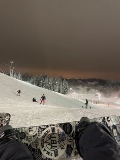 someone is sitting down on the snow with their feet up in front of them, while others are skiing