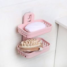 two pink plastic baskets with toothbrushes and soap on them hanging from the wall