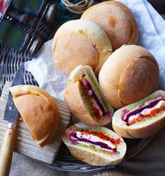 several rolls with different colored fillings in a basket next to a spatula and knife