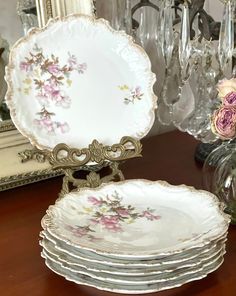 a stack of plates sitting on top of a wooden table next to a vase filled with flowers