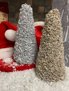 three small christmas trees sitting on top of a pile of white fluffy snow covered ground