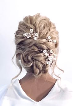 a woman with blonde hair wearing a white shirt and some flowers in her hair is seen from the back