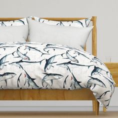 a bed with shark print on it and white pillows, along with wooden headboard