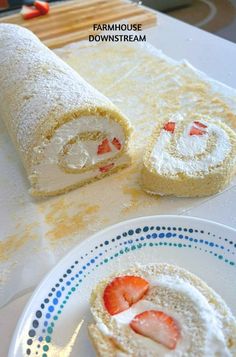 a roll with strawberries and cream on it sitting on a plate next to another roll