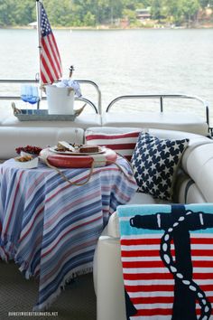 a living room filled with furniture covered in american flag blankets and throw pillows on the back of a boat