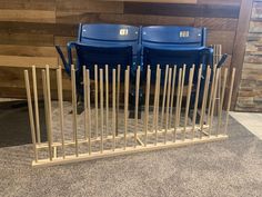 two blue chairs sitting next to each other in front of a wooden wall