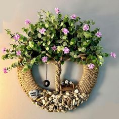 a fake tree with pink flowers is hanging on the wall next to a rock circle