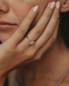 a close up of a woman's hand with a diamond ring on her finger