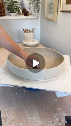 a person is making a bowl on top of a table in the middle of a room