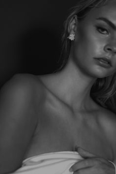 a woman in a white dress is posing for a black and white photo with her hand on her shoulder