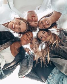 a group of young people standing in a circle looking up at the camera and smiling