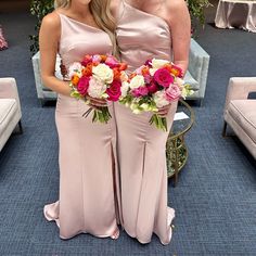 two women in long dresses standing next to each other with flowers on their bouquets