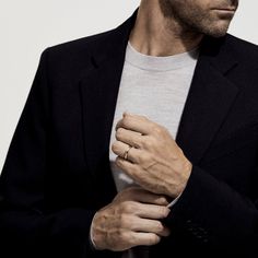 a man in a black suit and white shirt is holding his hand on his chest