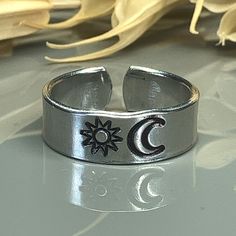 Handmade, Hand Stamped, Sun and Moon Aluminum Ring; Custom Made to Size This ring has a sun and moon hand stamped onto a non tarnishing 6mm aluminum band.  The ring is adjustable by about a size or two either up or down from the size you choose. The ring design can be left natural or darkened (as pictured) Aluminum is a lightweight metal that is hypoallergenic and does not tarnish! Each custom ring I make is handmade by hand hammering symbols into the metal so each design may not be perfectly st Adjustable Moon Shaped Bohemian Rings, Bohemian Moon Shaped Adjustable Rings, Bohemian Adjustable Moon-shaped Rings, Adjustable Ring With Sun And Moon Design, Adjustable Moon Shaped Symbolic Rings, Adjustable Sun And Moon Design Rings, Adjustable Nickel-free Moon-shaped Ring, Symbolic Moon-shaped Adjustable Rings, Adjustable Hypoallergenic Crescent Jewelry