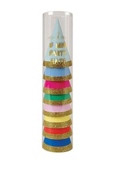 a stack of colorful party hats on top of a tall glass vase with gold glitter