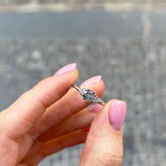 a woman's hand holding a diamond ring in front of her face on the street