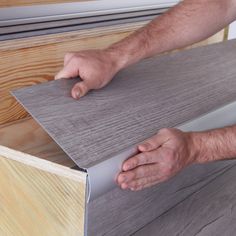 a man is holding the edge of a piece of plywood