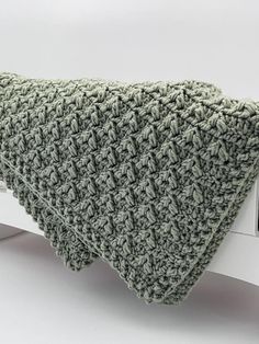 a green knitted pillow sitting on top of a window sill