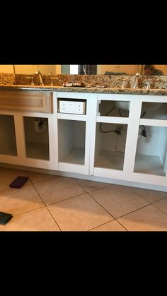 a kitchen with white cabinets and tile flooring in front of the counter top area