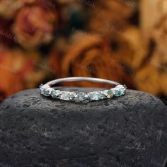 an image of a wedding ring on top of a rock with flowers in the background