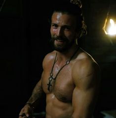 a shirtless man with no shirt on holding a knife in his right hand and looking at the camera