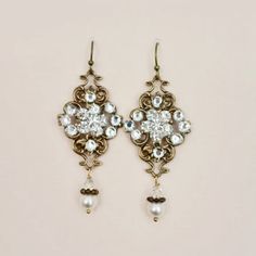 This pair of antique gold earrings feature vintage stampings by holding simulated ivory pearls for a fabulous bride in vintage style.It is handcrafted in our studio to add a special touch to your glamorous look.*Measurement :Length 2.5" Ornate Bridal Earrings For Formal Occasions, Ornate Bridal Earrings For Festive Occasions, Antique Gold Jeweled Earrings, Victorian Wedding Earrings With Intricate Design, Elegant Bridal Earrings With Intricate Metal Design, Elegant Bronze Brass Jewelry, Elegant Vintage Charm Jewelry For Anniversary, Intricate Victorian Wedding Earrings, Victorian Pearl Earrings For Wedding