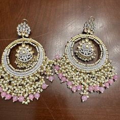 Elevate your style game with these exquisite Indian XLRG Kundan Gold Tone Party/Wedding Fashion Style Chandbali Earrings in Pink. The intricate design of these earrings features a round shape with a screw back closure, making them perfect for any occasion from engagement to graduation, wedding to Halloween. The natural Kundan stone adds a touch of elegance to the piece, while the brass metal and alloy base provide durability and long-lasting wear. The chandelier and dangle/drop style of these ea Wedding Chandbali Danglers, Chandbali Danglers For Party, Festive Party Beaded Latkan Earrings, Festive Party Beaded Earrings With Latkans, Bollywood Style Danglers For Wedding, Chandbali Chandelier Earrings For Party, Chandbali Chandelier Earrings For Party Festivals, Kundan Chandbali Party Danglers, Kundan Chandbali Danglers For Party