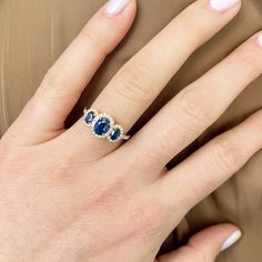 a woman's hand wearing a ring with two blue stones on the middle of it