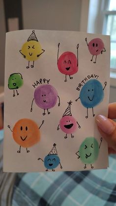 someone is holding up a birthday card with happy faces on it and the words happy birthday written in different colors