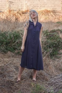 "this gorgeous vintage dress appears to be 50's inspired, with 70's boho flair. a dark navy blue with  white polka dots, collar, and white buttons down the entire front, the dress is also a bit sheer (see photos). will look nice with a slip underneath, and even with a belt to cinch in the waist (not pictured). appears to be in wonderful conditions despite its age, and would look gorgeous with some brown espadrille sandals or vintage heels - or make it casual, and pair it with some vintage lace-u Collared Summer Dress With Buttons, 1950s Style Polka Dot Dresses For Spring, Spring Polka Dot Collared Dresses, Spring Polka Dot Vintage Dress, 1950s Style Fitted Spring Midi Dress, Summer Polka Dot Fitted Midi Dress, Summer Fitted Polka Dot Midi Dress, Fitted Polka Dot Midi Dress For Summer, Retro Button-up Spring Dress