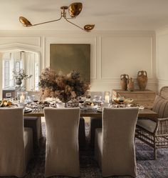 a dining room table is set with place settings for four people and there are vases on either side of the table