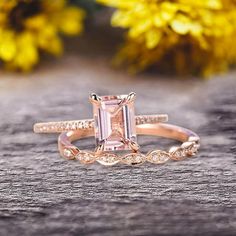 an engagement ring with a pink diamond in the center on top of a wooden table