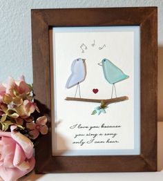 a couple of birds sitting on top of a wooden frame next to flowers and a vase