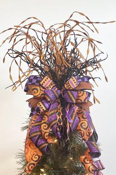 a purple and orange bow on top of a christmas tree