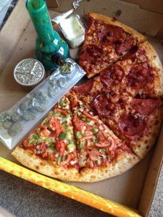 a pizza sitting inside of a box next to a knife and some condiments