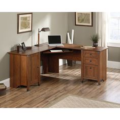 a computer desk with a laptop on top of it in front of a wooden floor