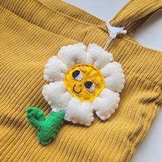 a yellow sweater with a white flower on it and a green cactus brooch attached to the front