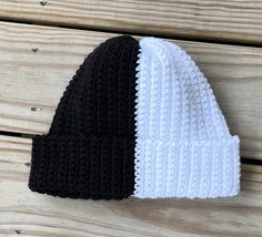 two black and white knitted hats sitting on top of a wooden table