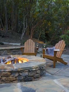 an outdoor fire pit with two chairs around it