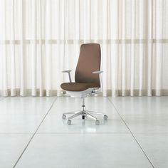 an office chair sitting on top of a white floor next to a window with curtains