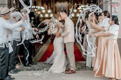 a bride and groom kiss as their guests throw streamers in the air at them