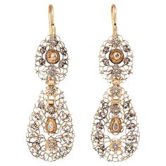 A pair of 15 carat gold and silver Georgian Flemish long earrings, with a lace like design, the earrings have been constructed from gold plate completely open worked with scrolls and flowers decorated with rose cut diamonds set in gold and silver, the bottom pendant holds a dangling inner drop, Belgium, circa 1820. weight: 16.12 grams dimensions: 7.8 x 2.3 cm